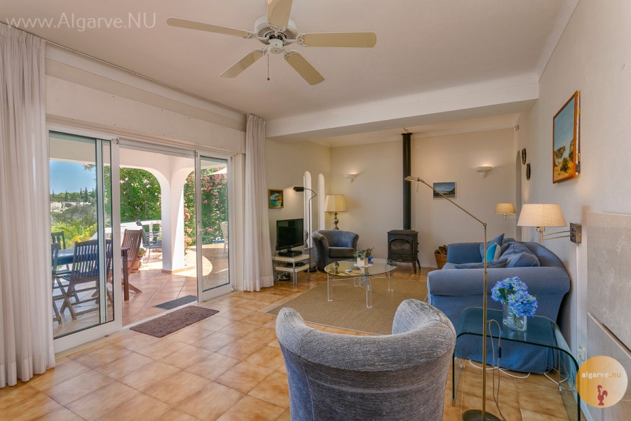 Ruime woonkamer met toegang tot het gedeeltelijk overdekte terras en het zwembad. Airco, verwarmingspanelen,TV, Wifi, houtkachel, spelletjes aanwezig.